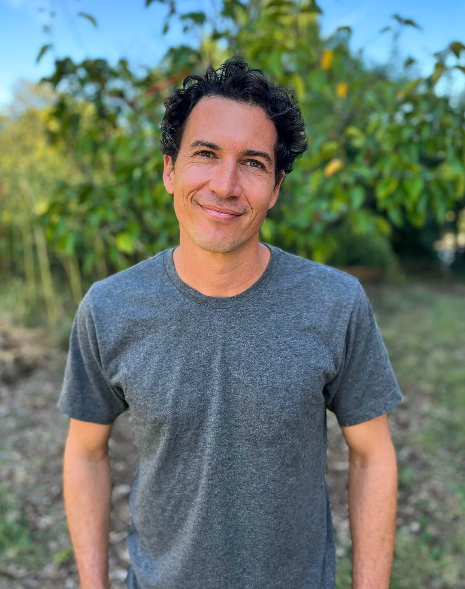Man in blue tshirt standing in a fruit orchard